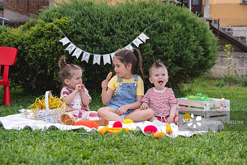 在家庭庆祝和聚会期间，恶作剧的兄弟姐妹玩耍并吃复活节装饰品图片素材
