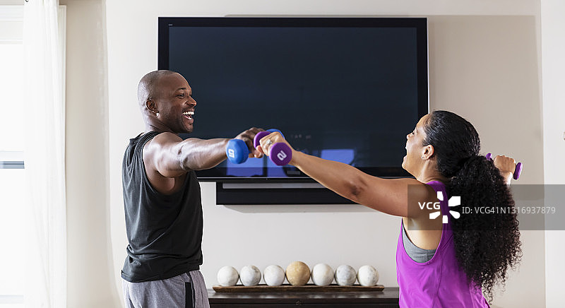 情侣在液晶电视前用哑铃锻炼图片素材