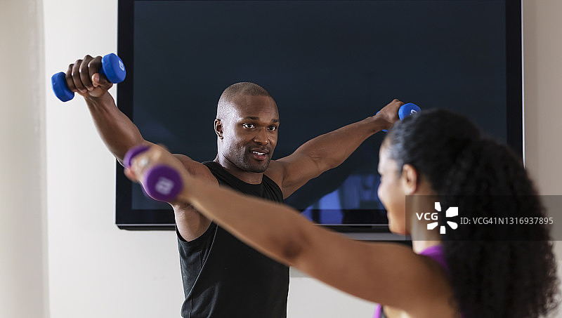 情侣在液晶电视前用哑铃锻炼图片素材