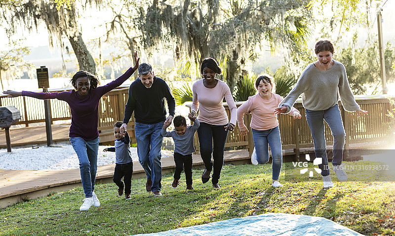 混合家庭与五个孩子在公园里奔跑图片素材