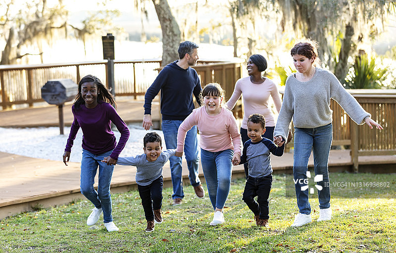 混合家庭与五个孩子在公园里奔跑图片素材