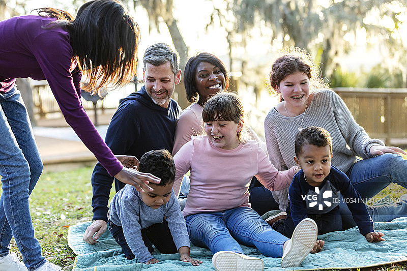 混合家庭与五个孩子坐在公园里图片素材