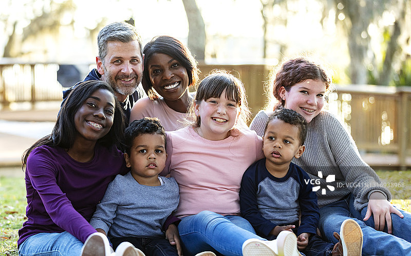 混合家庭与五个孩子坐在公园里图片素材