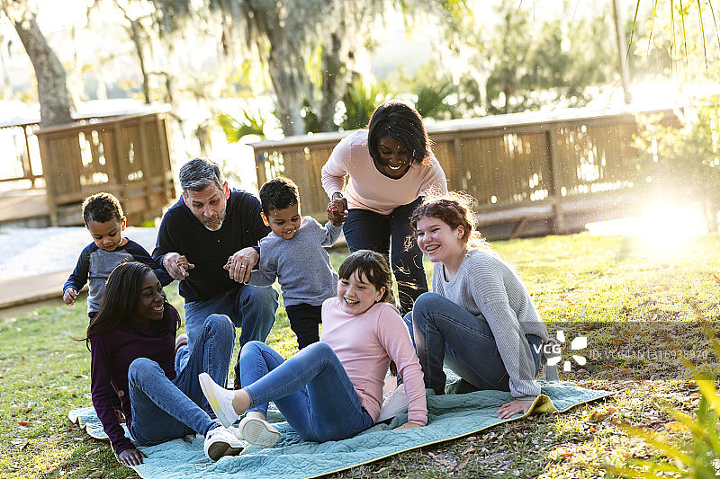 公园里铺着毯子的五孩重组家庭图片素材