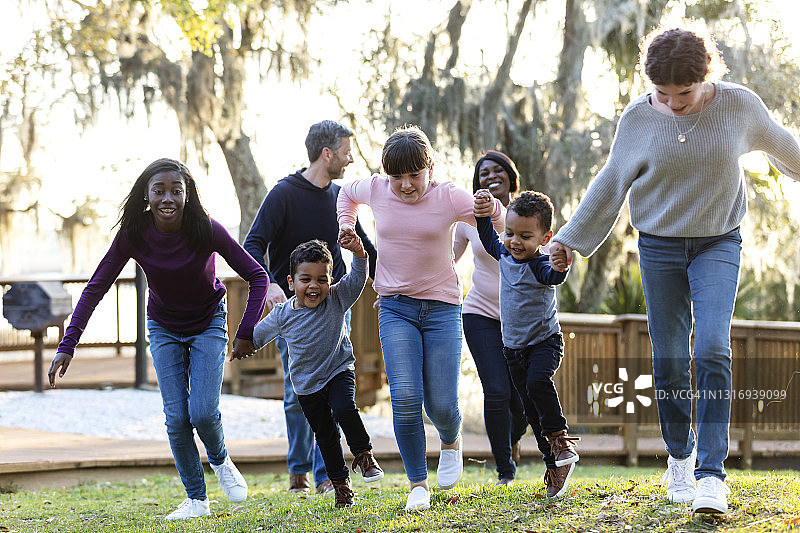 混合家庭与五个孩子在公园里奔跑图片素材