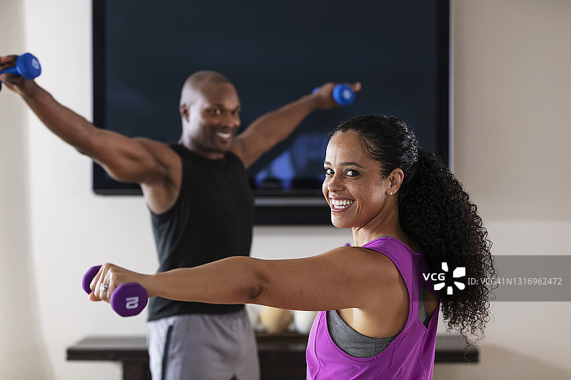 情侣在液晶电视前用哑铃锻炼图片素材