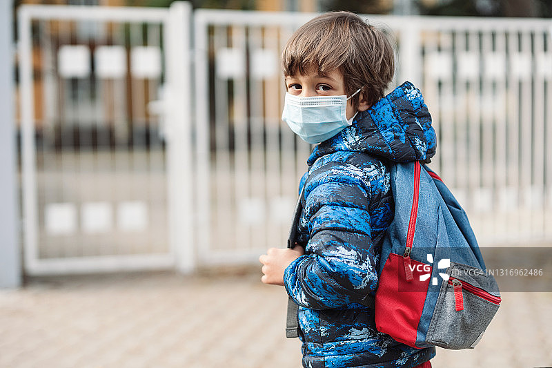 戴着口罩看镜头的男学生图片素材