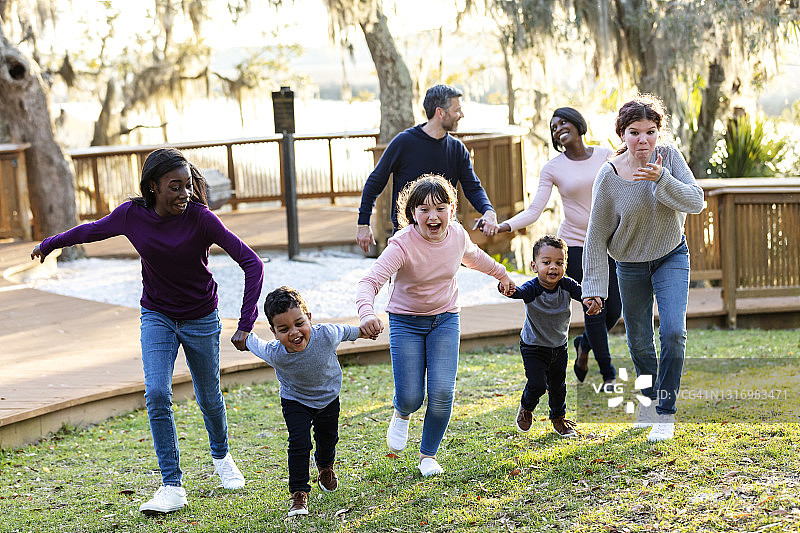 混合家庭与五个孩子在公园里奔跑图片素材