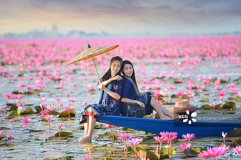 两位美丽的女人在泰国一个长满粉红色莲花的湖上航行图片素材