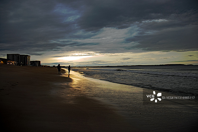 情侣在美国缅因州老果园海滩欣赏日出图片素材