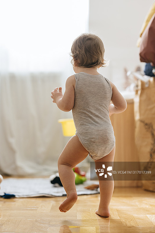 穿连体衣的女婴在家走路图片素材