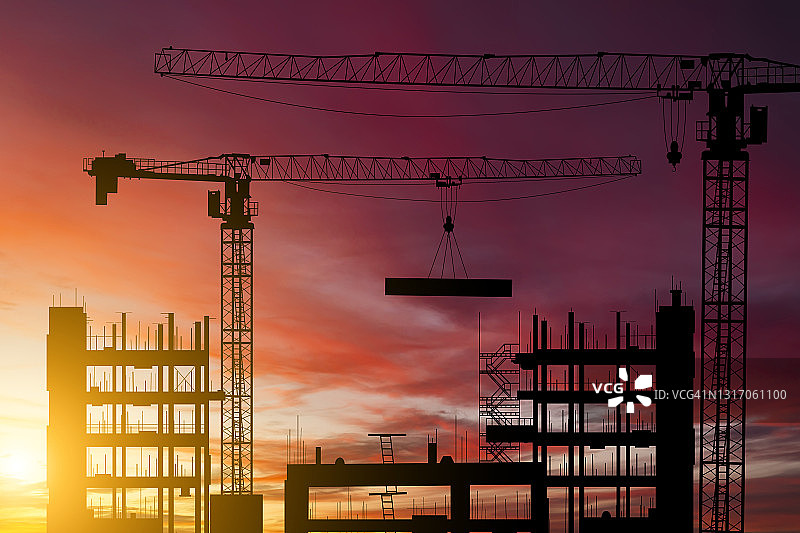 夕阳下的建筑工地与起重机：公寓楼建造图片素材