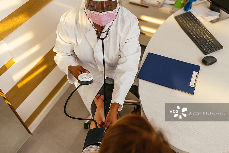 疫情期间，黑人女医生为病人测量血压图片素材