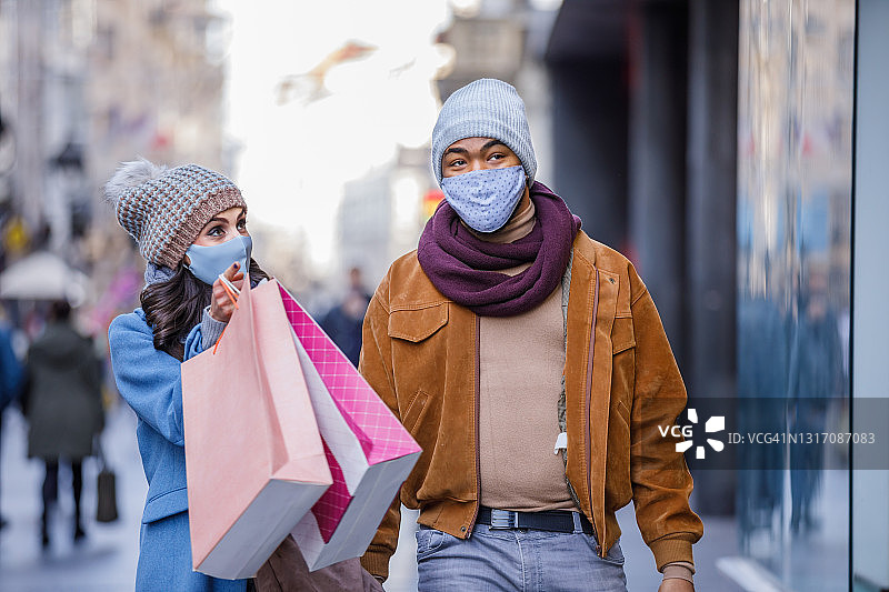 疫情期间携带购物袋散步的快乐的多元种族夫妇肖像图片素材