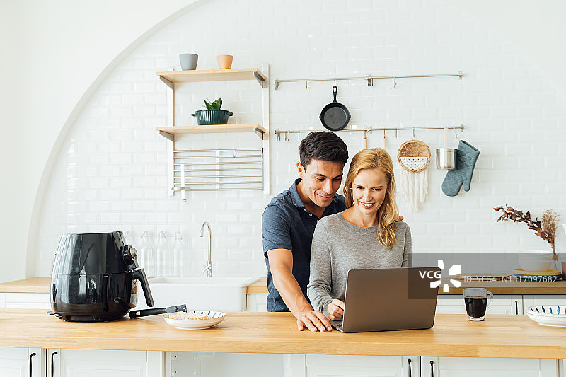 情侣在厨房使用笔记本电脑图片素材