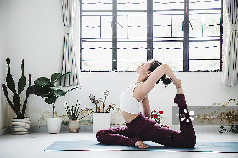 亚洲女人在瑜伽馆练习单腿鸽王式图片素材