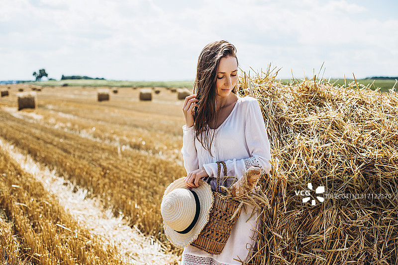 身穿白色连衣裙的年轻漂亮女人手提篮子图片素材