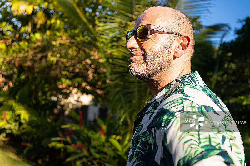 在热带花园里戴着夏威夷衬衫和太阳镜的成年男子轮廓图片素材