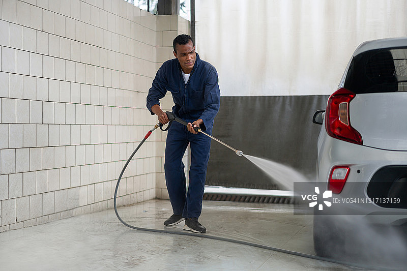 男人在洗车场用水管清洗车辆图片素材