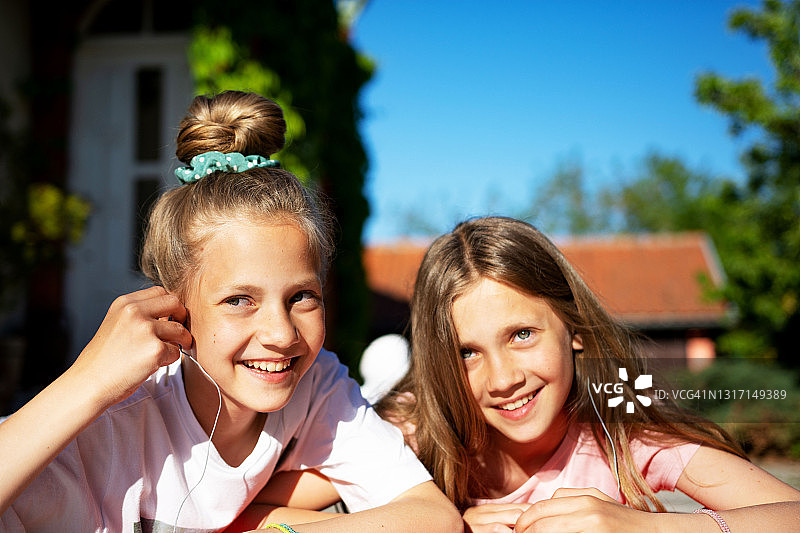双胞胎姐妹分享耳机听音乐图片素材