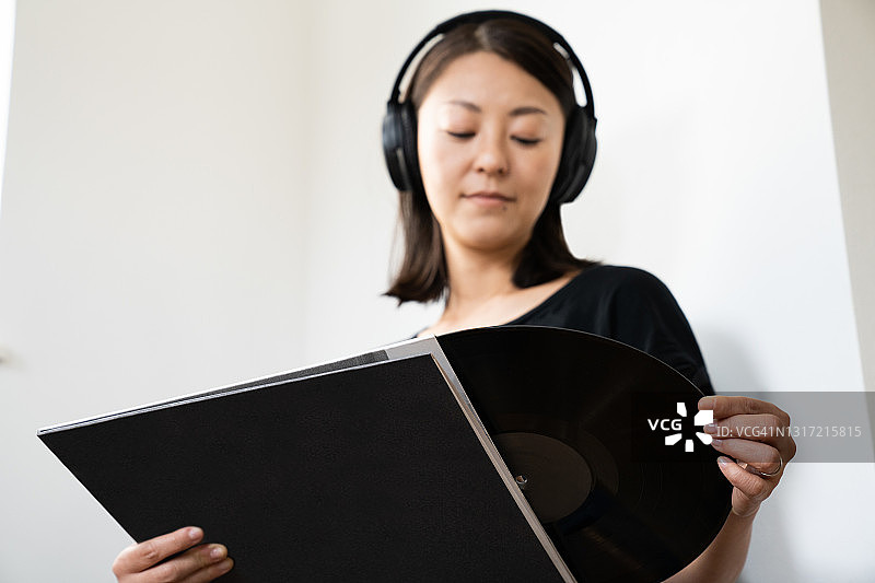 年轻女子在家听黑胶唱片图片素材