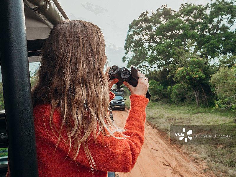在豪华野生动物园中使用双筒望远镜寻找野生动物的快乐年轻女人图片素材