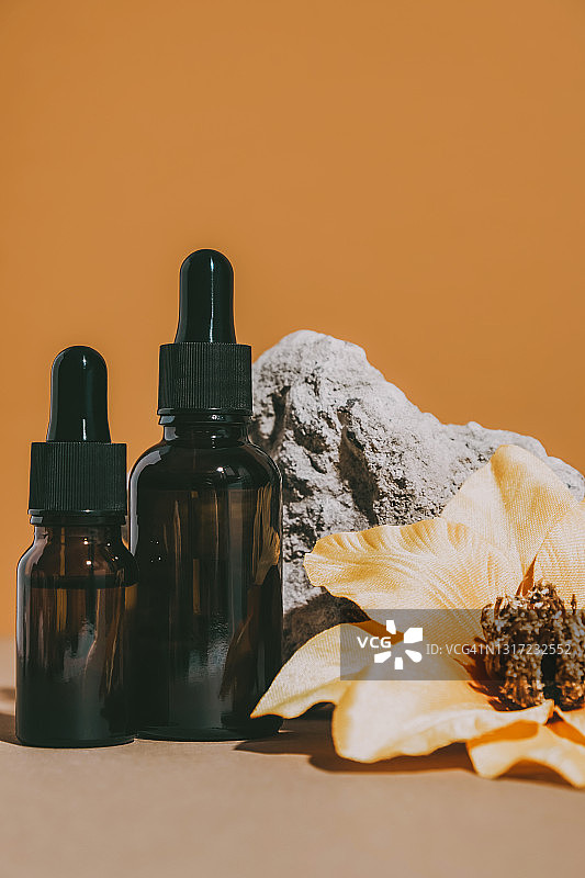 带滴管的棕色化妆罐，搭配石头和鲜花图片素材