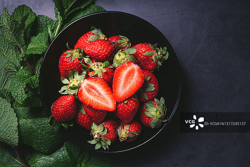 黑色背景上的一碗草莓图片素材