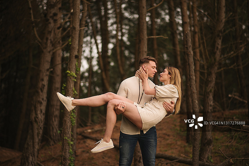 年轻男人在森林里举起他的女朋友图片素材