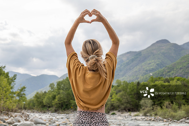 热爱自然的年轻女人用手比心图片素材