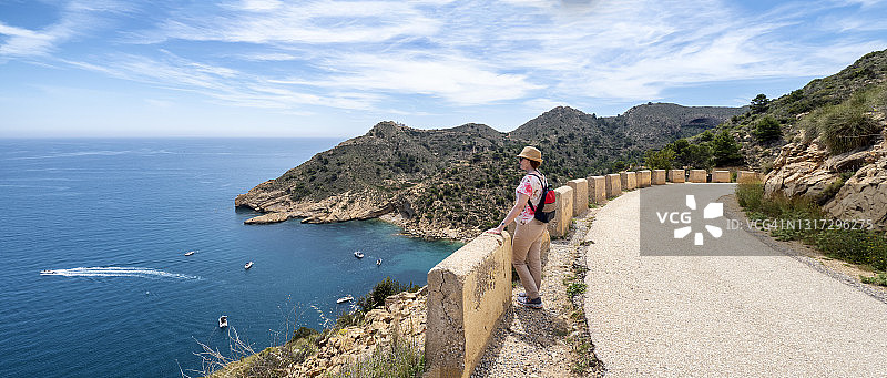 远足女性沿着海边的山路行走图片素材