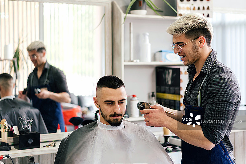 在理发店里，男理发师为男人理发图片素材