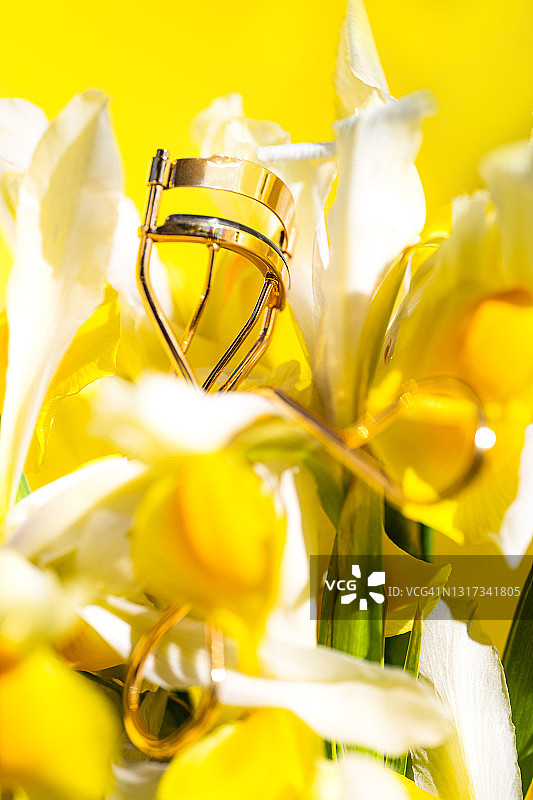 时尚美妆概念：睫毛夹与黄白花朵图片素材