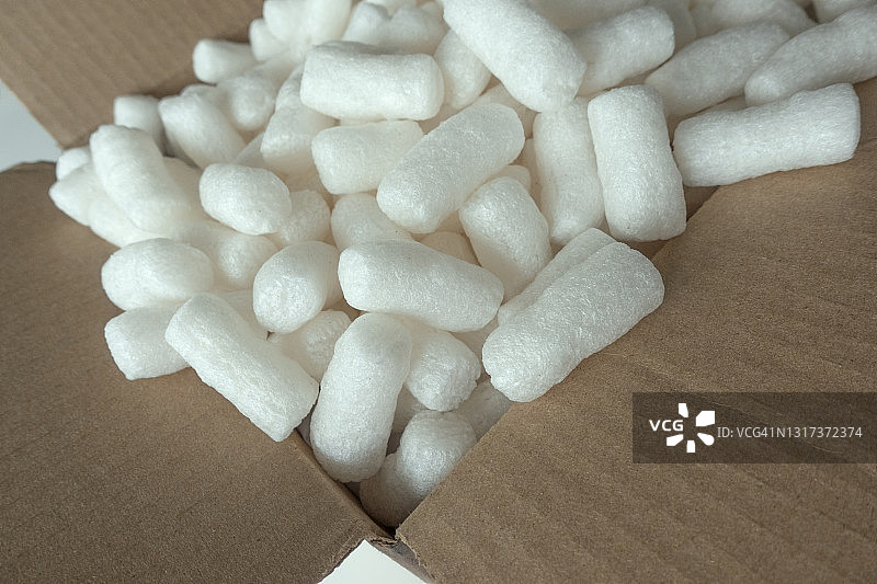 棕色纸板邮寄箱中的白色泡沫塑料花生或颗粒图片素材