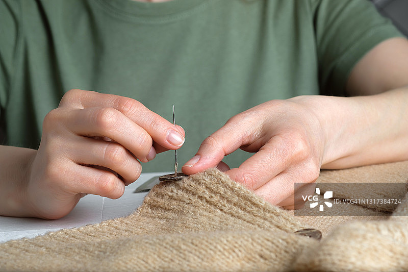 女人在针织毛衣上缝纽扣，特写镜头图片素材