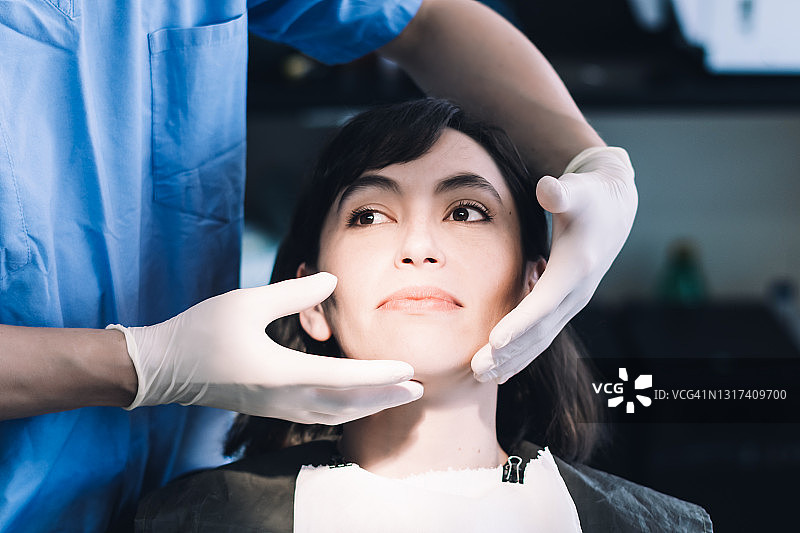 戴着蓝色帽子的牙医正在检查病人的牙齿图片素材