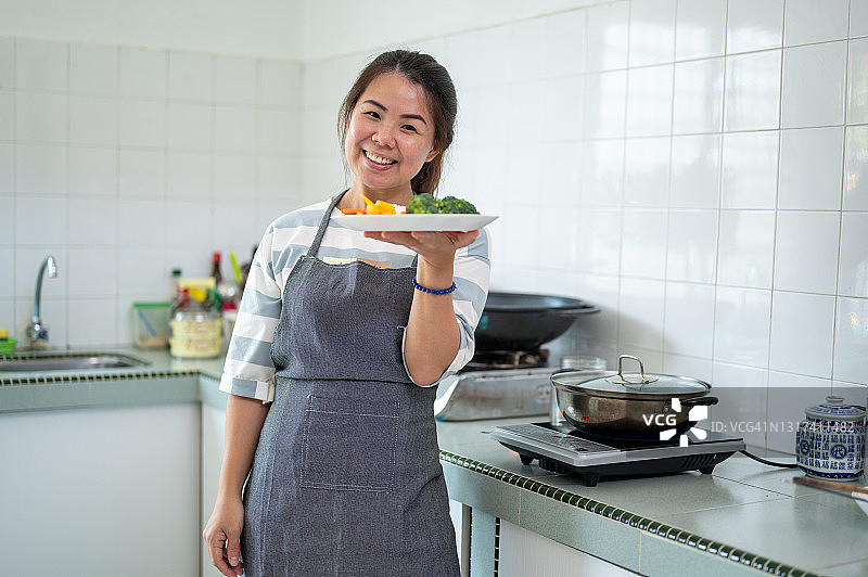 在厨房做饭的快乐亚洲女性图片素材