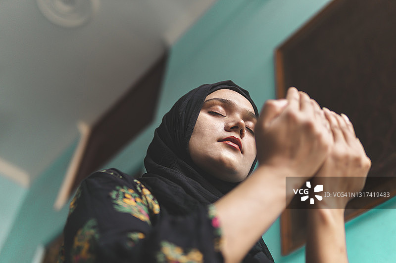 美丽的穆斯林妇女在家祈祷，斋月礼拜时间图片素材