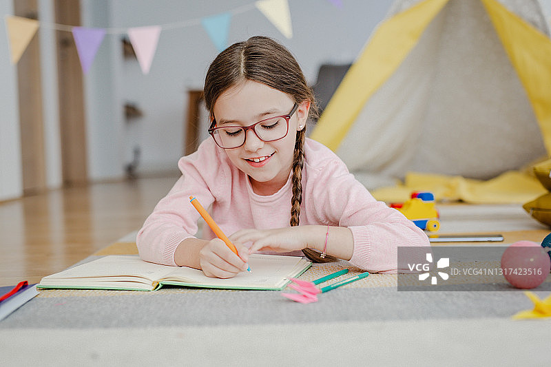 小女孩在家在地板上写作业图片素材