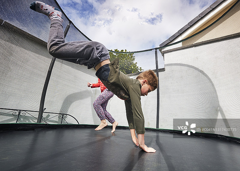 男孩和女孩在郊区蹦床上玩耍图片素材