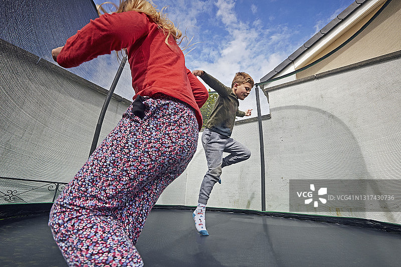 男孩和女孩在郊区蹦床上玩耍图片素材