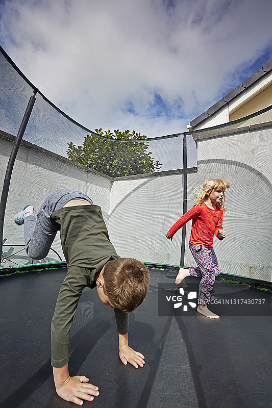 男孩和女孩在郊区蹦床上玩耍图片素材