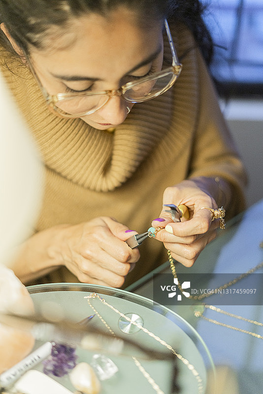拉丁女人在家里用美丽的石头制作项链图片素材