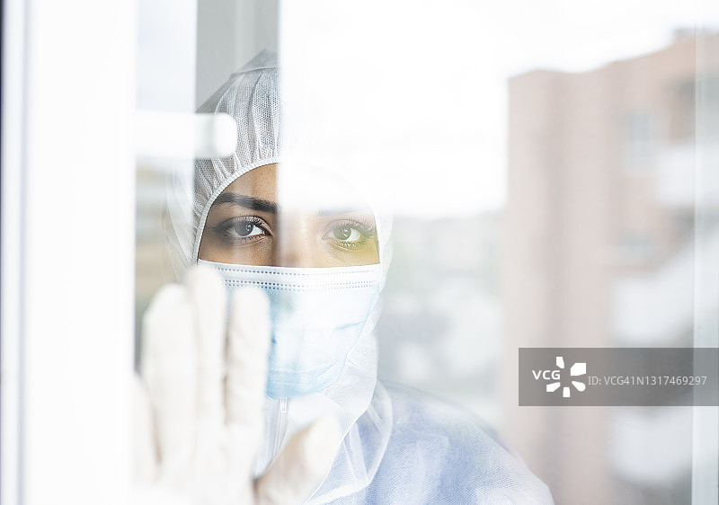 戴口罩的女医生望着窗外，面露悲伤图片素材