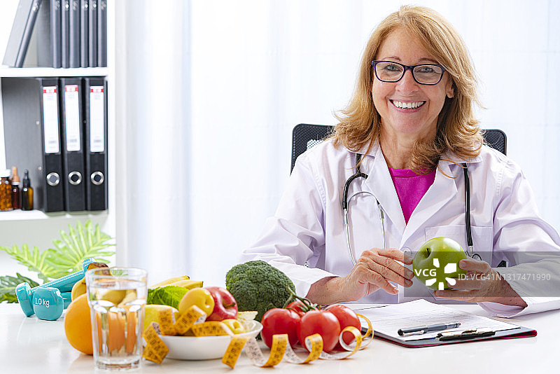 自信的女营养师拿着一个绿苹果图片素材