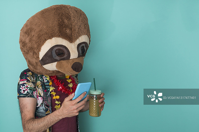 戴着猫鼬面具的有趣男孩在使用手机图片素材