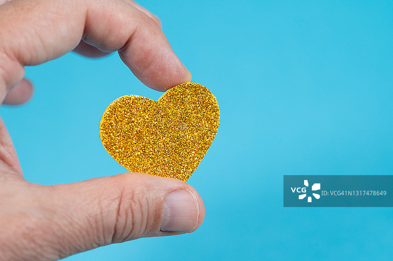 男人手持心形（蓝色背景）图片素材