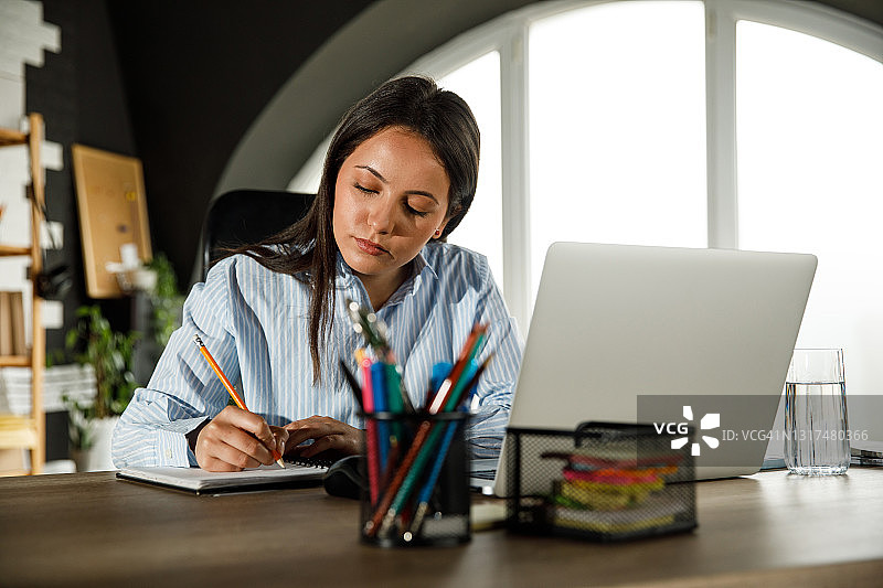 在办公桌前写“待办事项”的年轻女商人图片素材