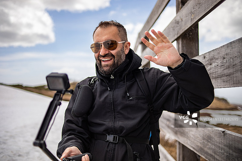 徒步旅行者爬山，用Gopro相机拍摄视频，为他的视频博客制作视频图片素材
