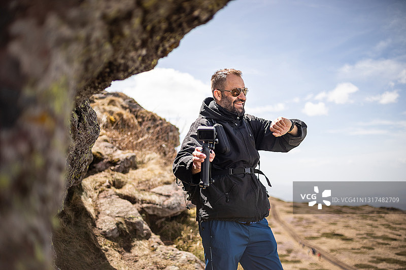 徒步旅行者爬山，用Gopro相机拍摄视频，为他的视频博客制作视频图片素材